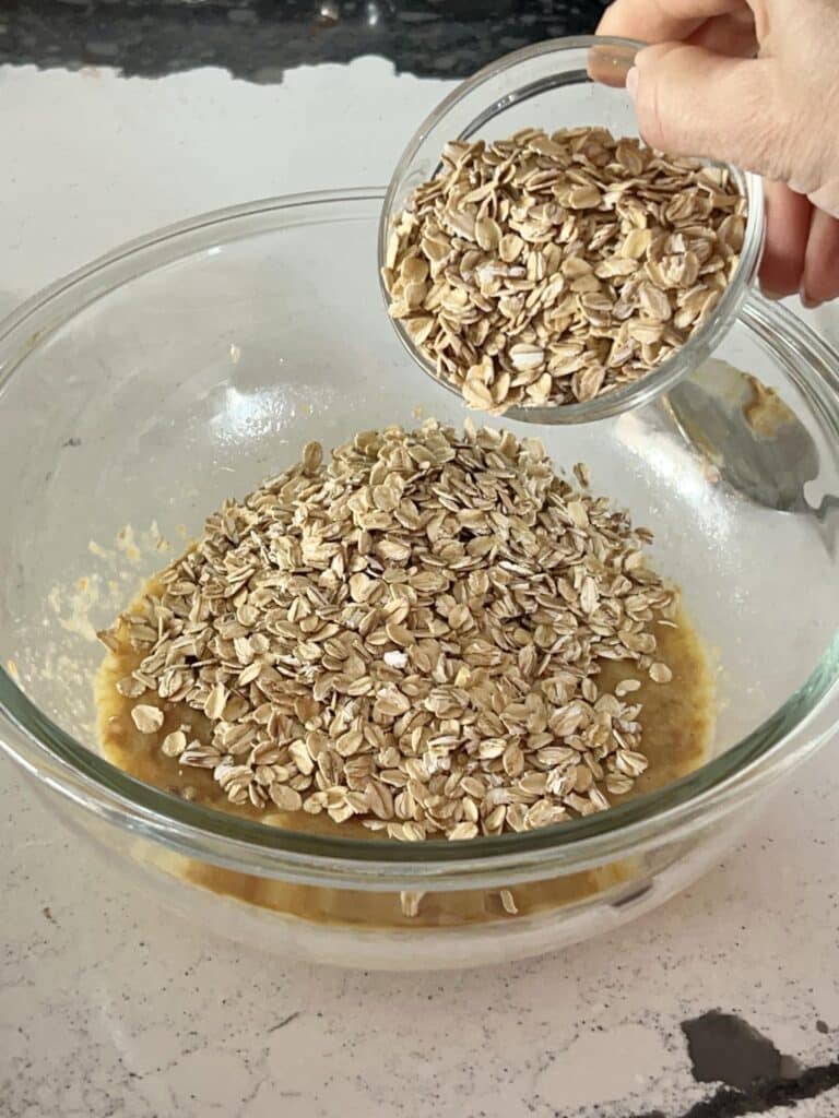 Adding rolled oats to a mixture.