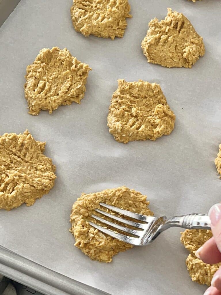 Using a fork to flatten dog treats.