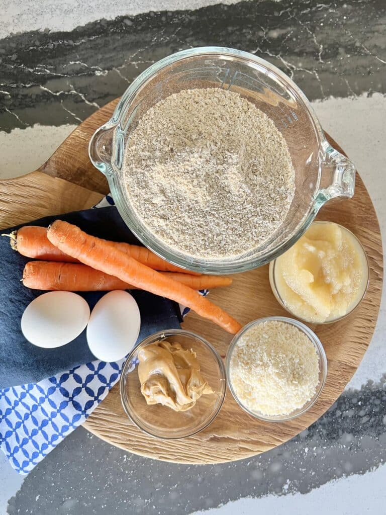 Oat flour, applesauce, coconut, peanut butter, eggs, and carrots used for Carrot homemade oatmeal dog treats.