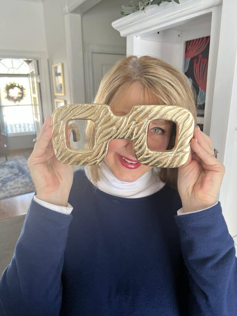 Missy holding some oversized home decor in the shape of reading glasses.