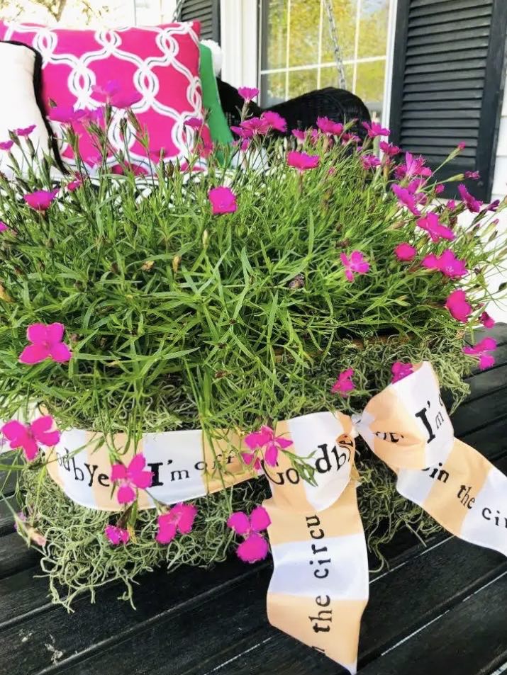 A moss covered May Day basket sitting on a front porch.