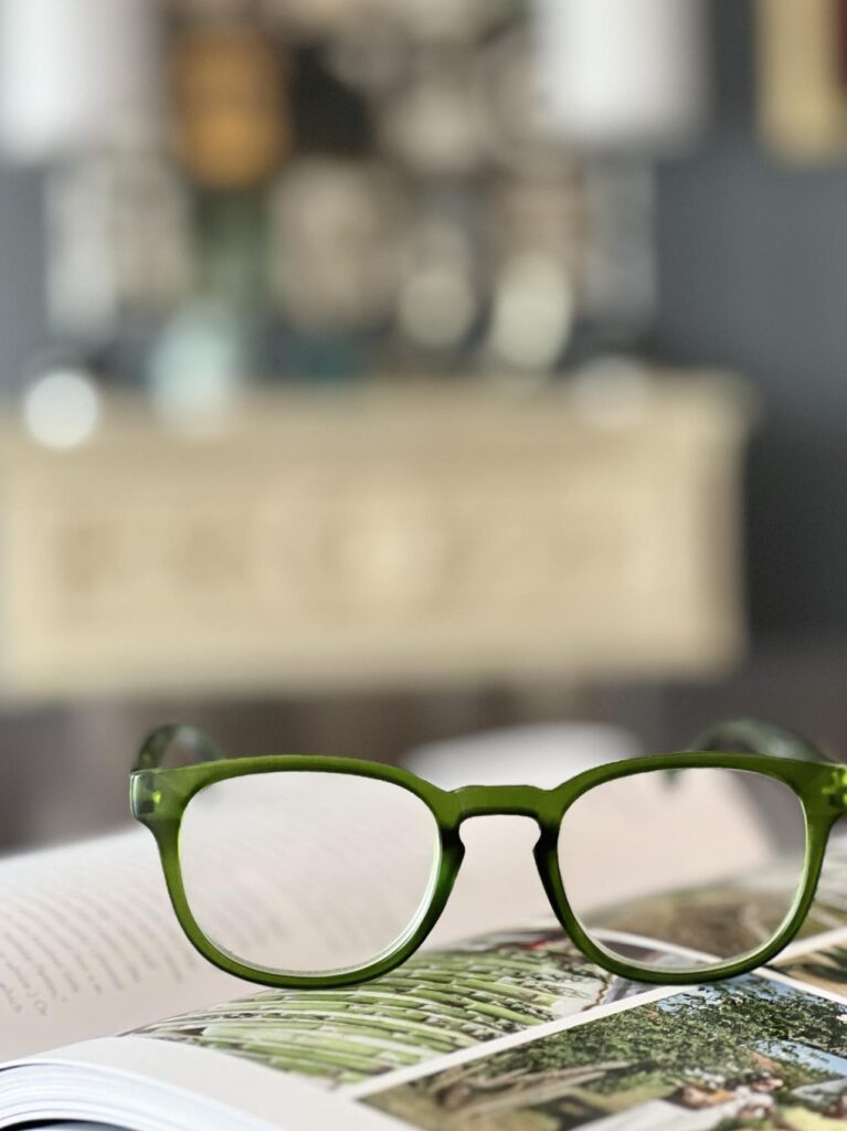 How to Wear Reading Glasses Stylishly: Green readers on top of an open book.