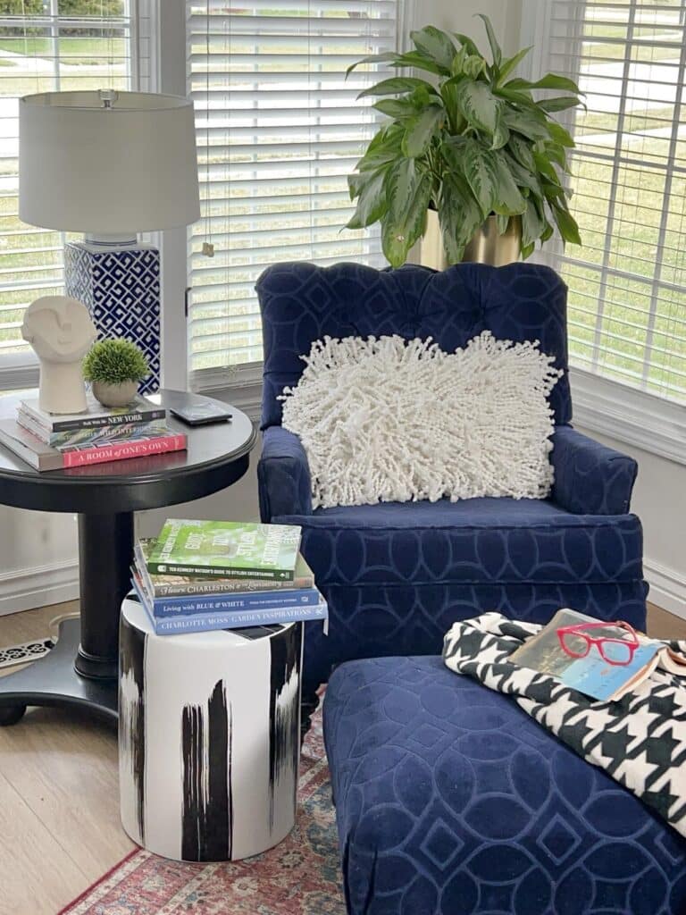 Reading nook ideas for bedroom start with a cozy blue chair with a white pillow and houndstooth blanket.