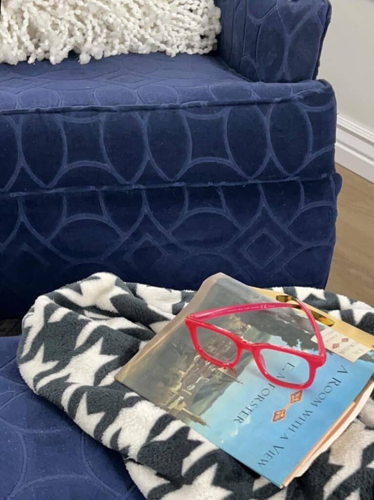 Red reading glasses sitting on top of a book.