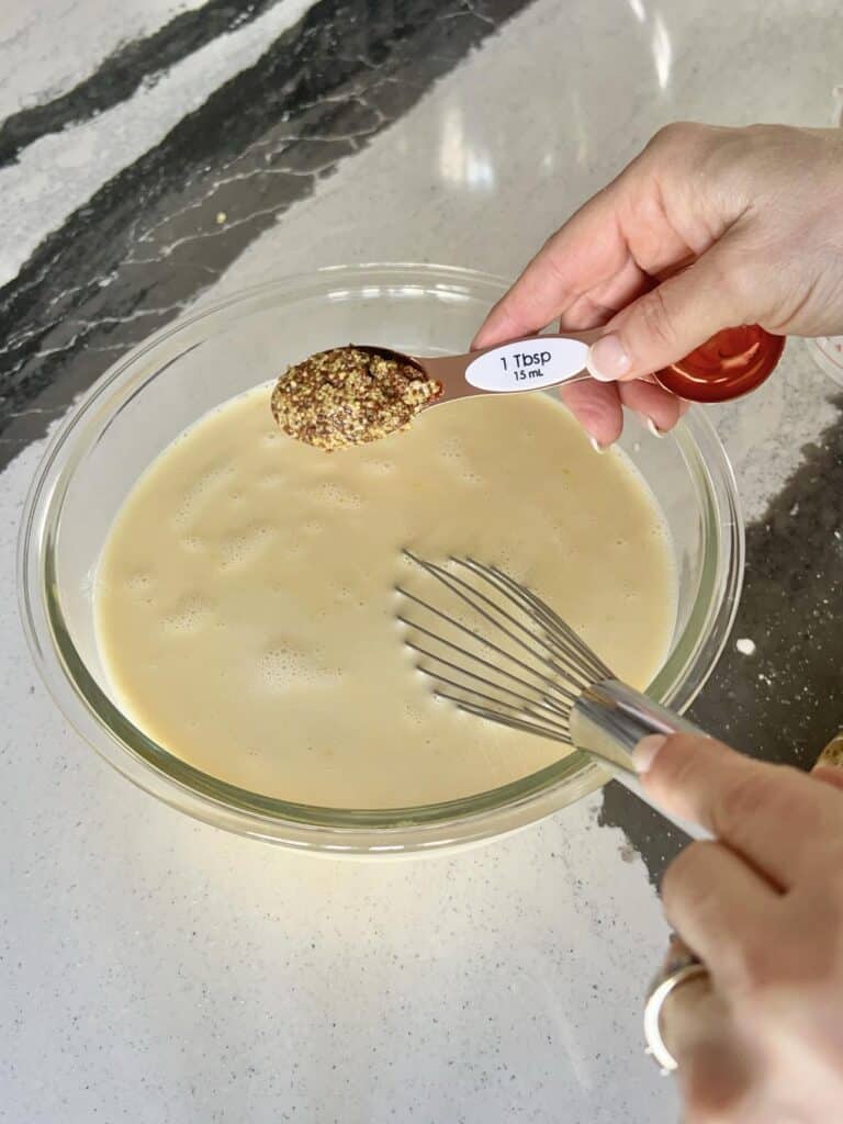 Adding dijon mustard to egg mixture.