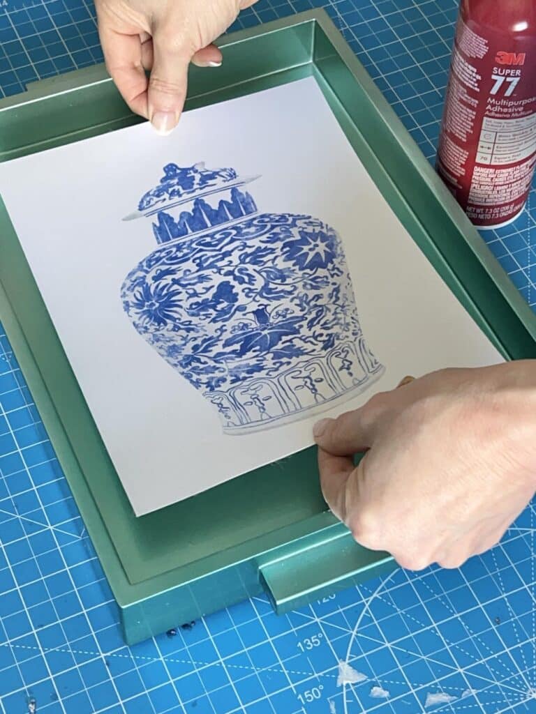 Adhering the art print to the bottom of a green tray.