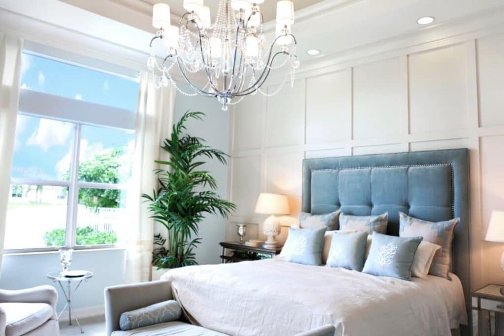 A blue tufted headboard and luxurious bedding are ideas to decorate a glamorous bedroom.