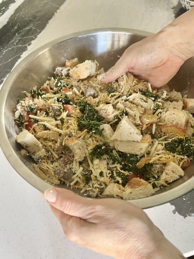 Mixing everything bagel casserole ingredients with hands.