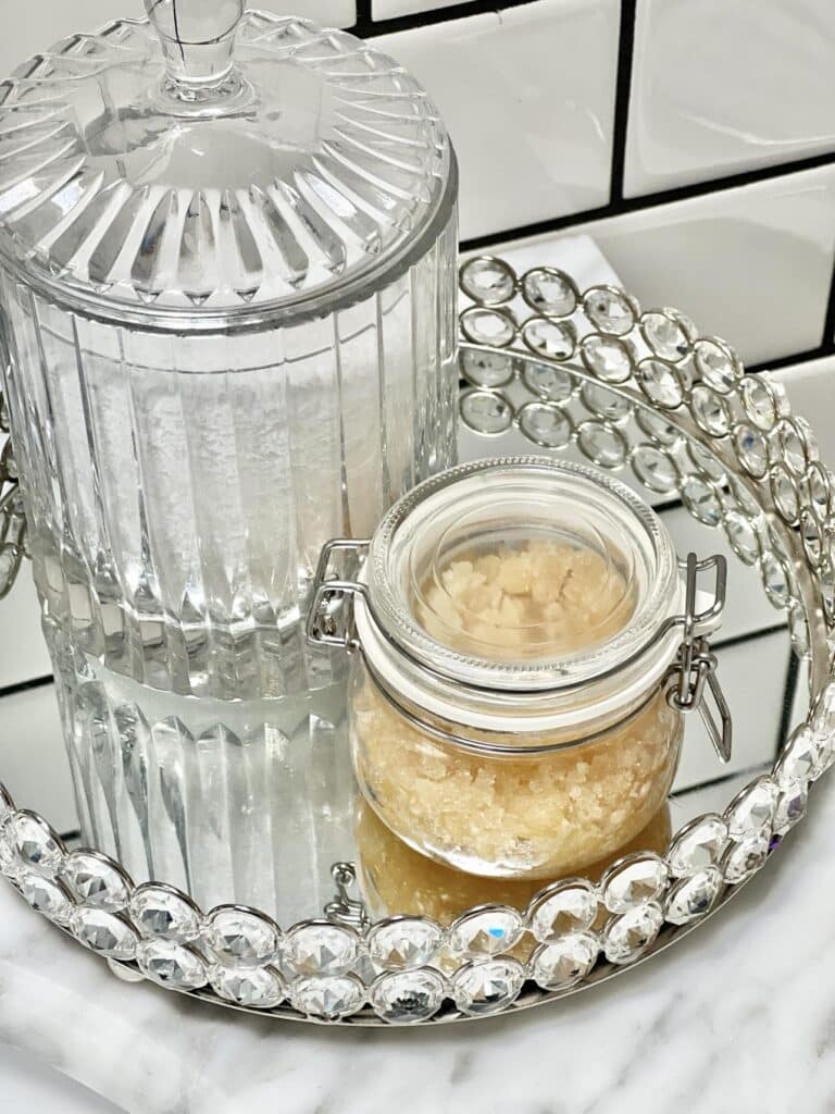 Crystal glass tray and glass jar filled with bath salts and sugar scrub.