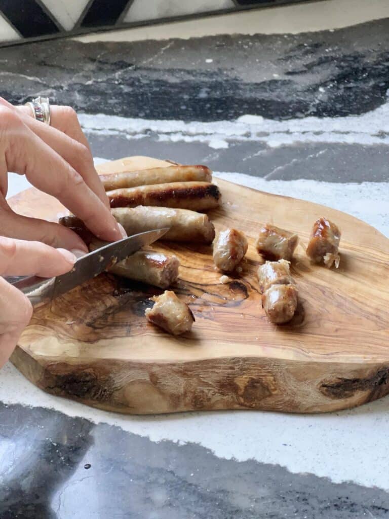 Cutting cooked breakfast sausage for everything bagel breakfast bake.