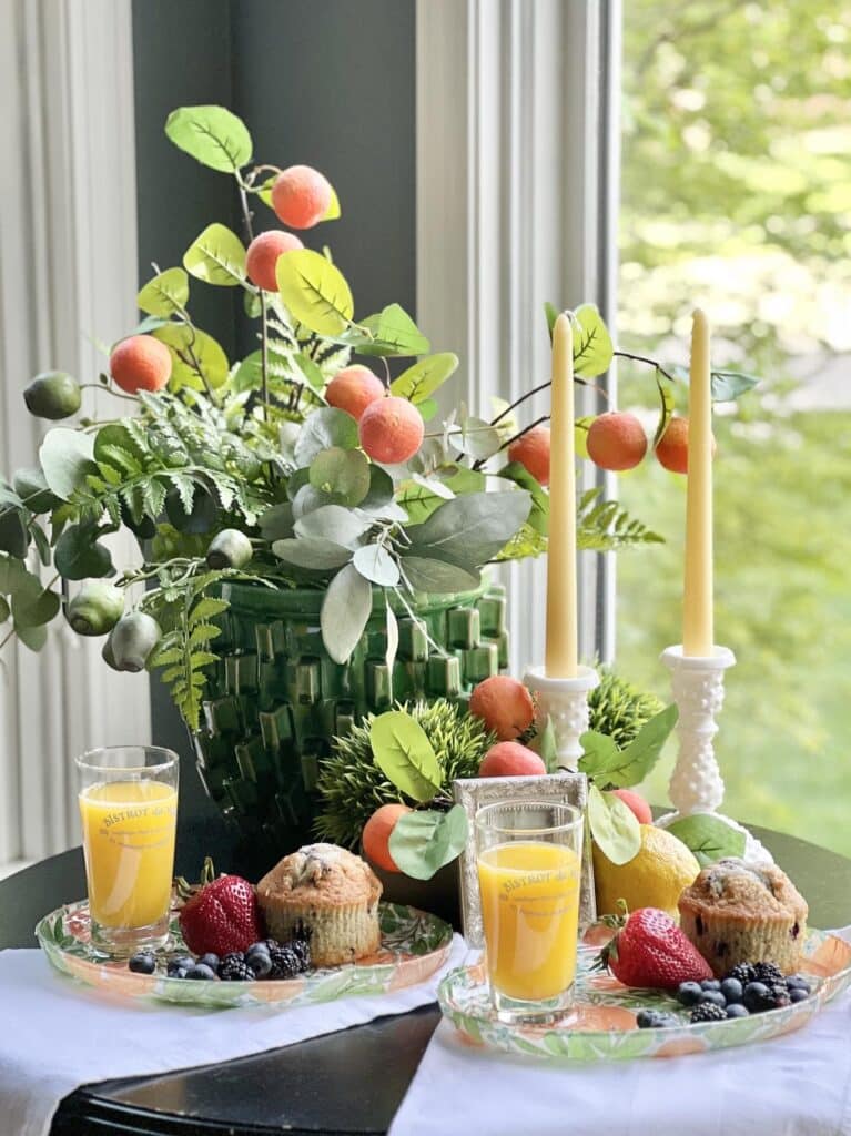 A table setting using greenery, orange branches, and decoupage glass plates.