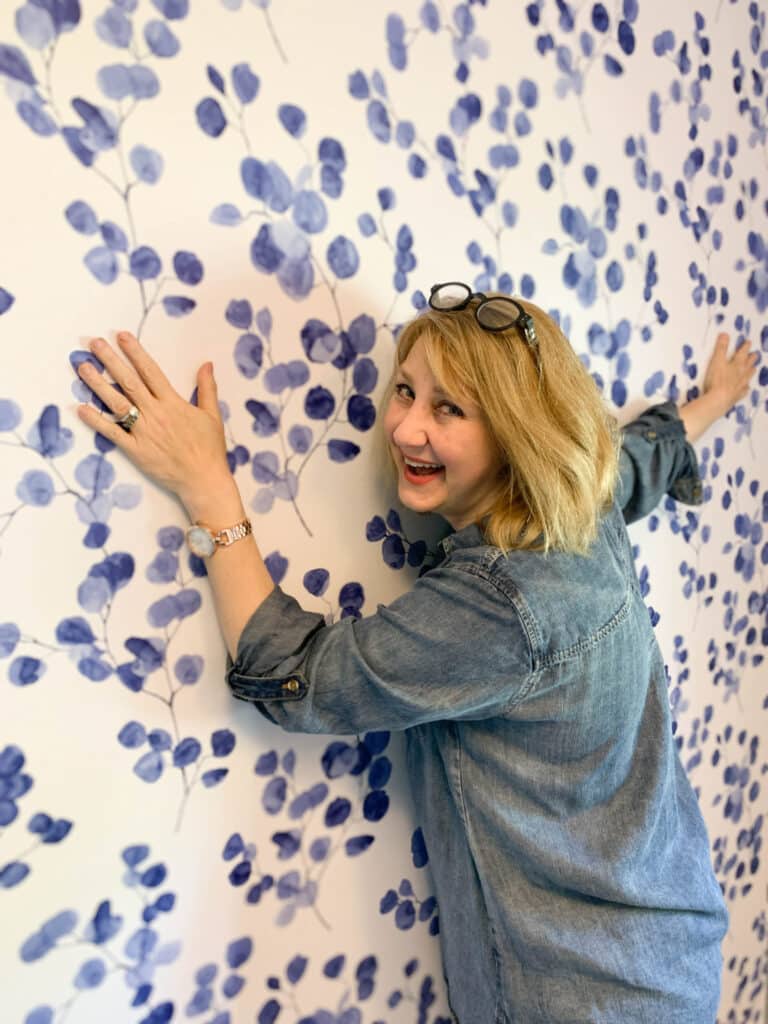 A woman hugging a wall covered in peel and stick wallpaper.