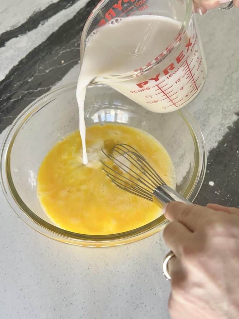 Pouring milk into egg mixture.