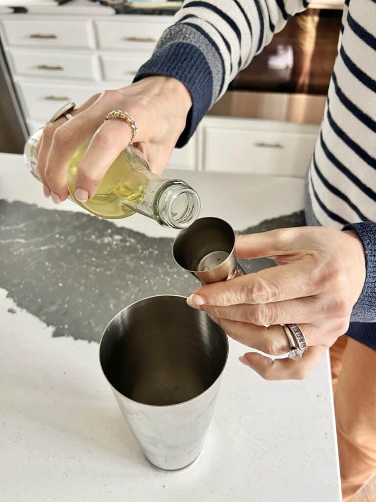 Pouring simple syrup to make a French 76.