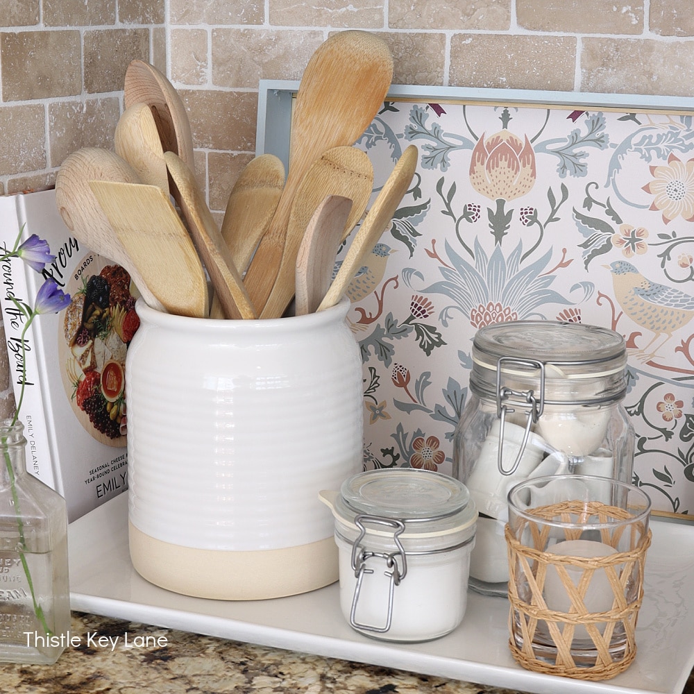 A wallpaper lined tray propped against the backsplash in the kitchen.