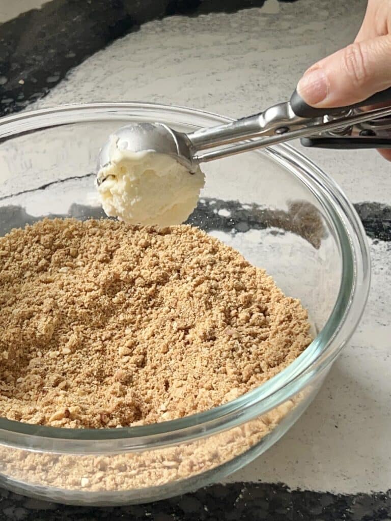 Cropping aa scoop of ice cream into a graham cracker coating.