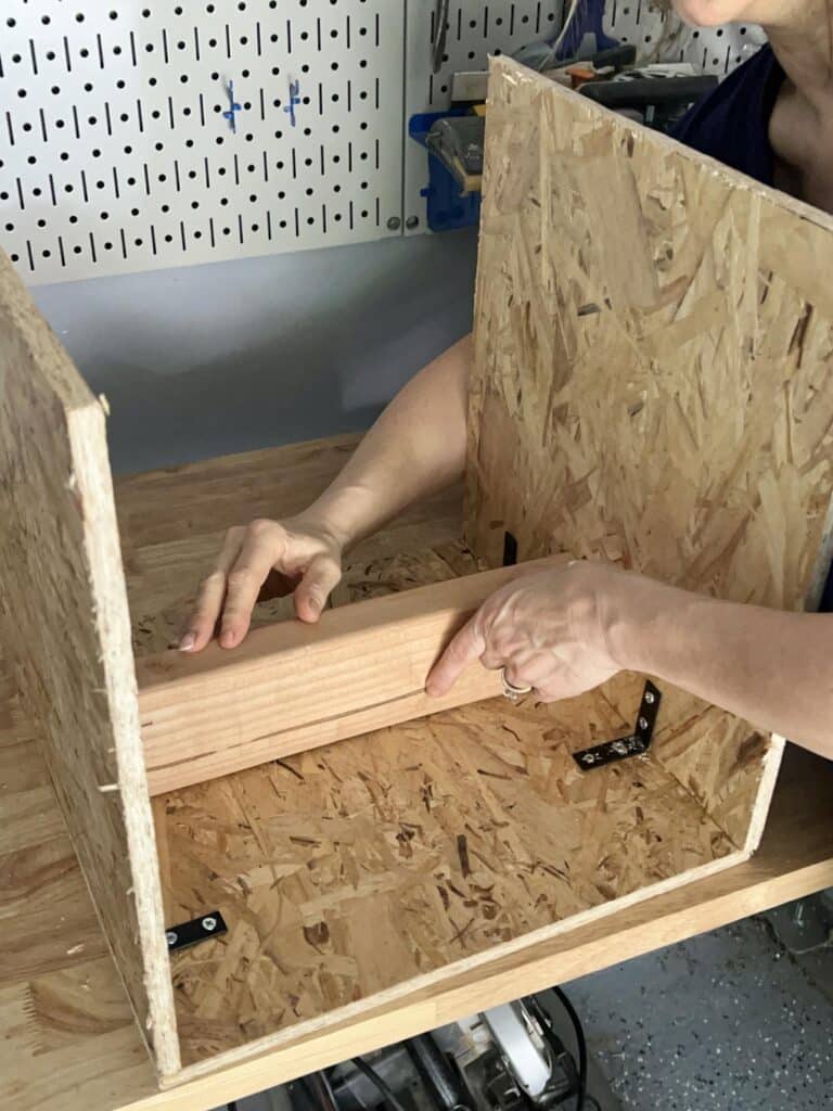 Placing a 2 x 4 as a temporary brace between pieces of OSB.
