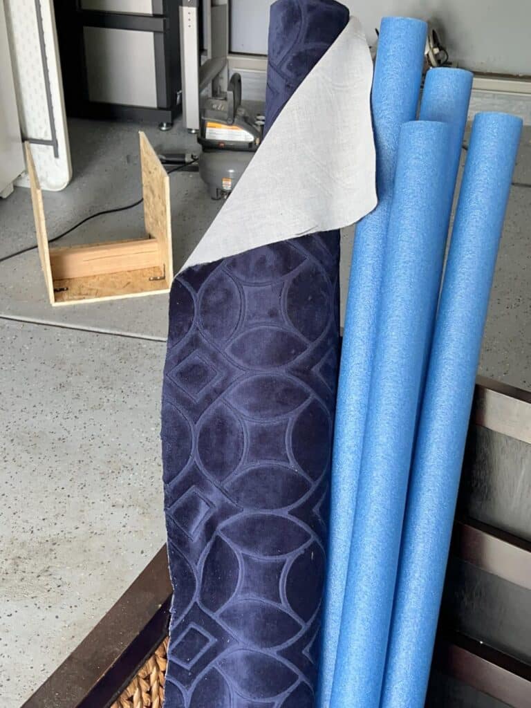 A bolt of fabric and four blue pool noodles.