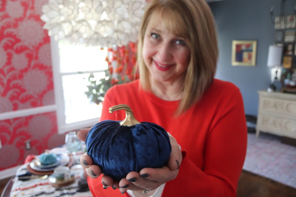 Woman holding a blue velvet pumpkin in her hands.
