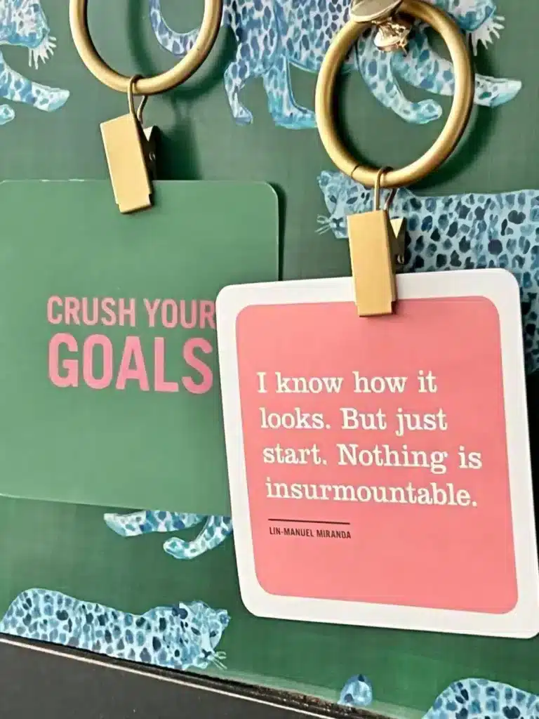 Quote cards hanging by clips on cork board.