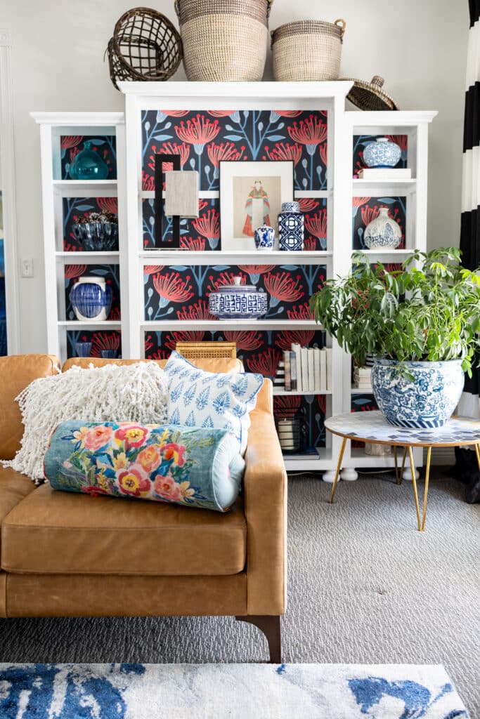 A white bookcase decorated for summer with various home decor.