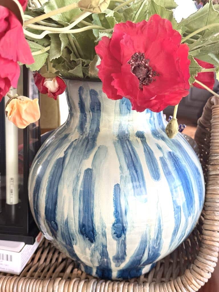 A blue and white metal vase and faux red poppies for a patriotic centerpiece.