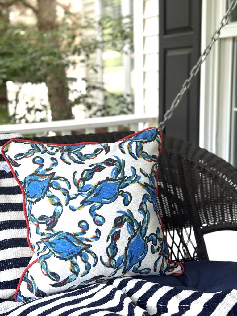 Coastal crab outdoor pillow styled on a front porch swing.