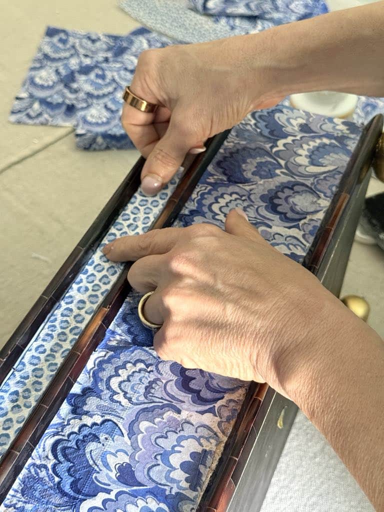 Gluing a leopard print paper napking to the side of a thrift store decor box.