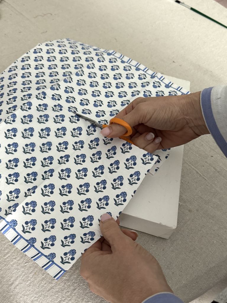 Cutting a blue and white paper napkin in half.