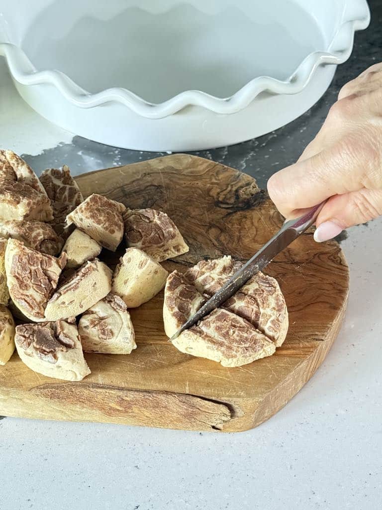 Cutting slices of cinnamon roll dough into fourths.
