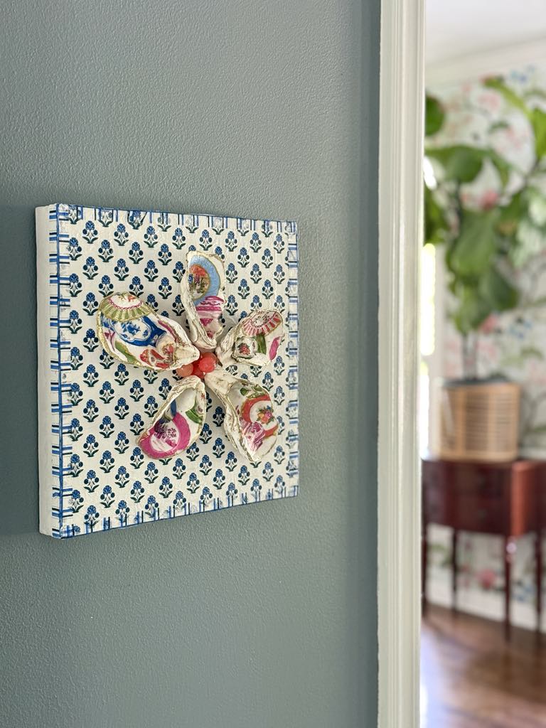 DIY decoupage shells flower wall art hanging on a dark grey wall.