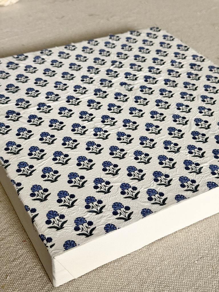 A wrapped canvas with a decoupaged napkin on top.
