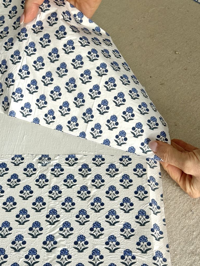 Applying a paper napking to a wrapped blank canvas with decoupage glue.
