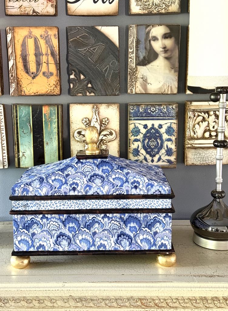 Decoupage thrift store decor box displayed on a sideboard with a lamp to the side.