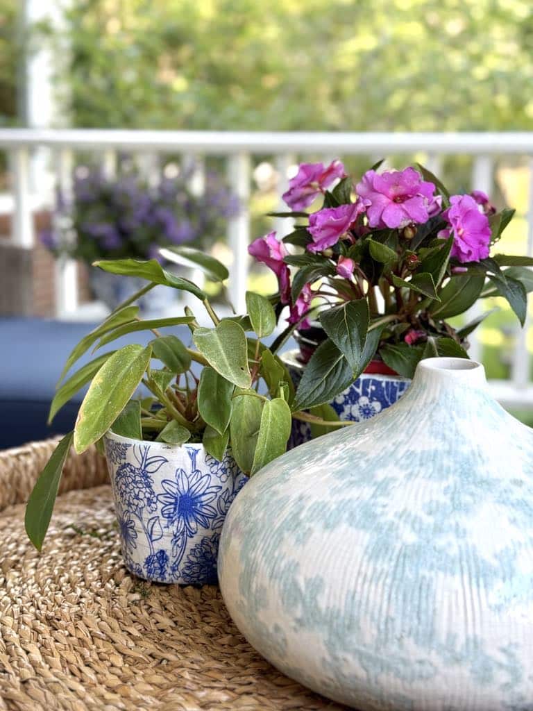 Decorating a front porch with potted flowers and a ceramic vase on an outdoor coffee table.