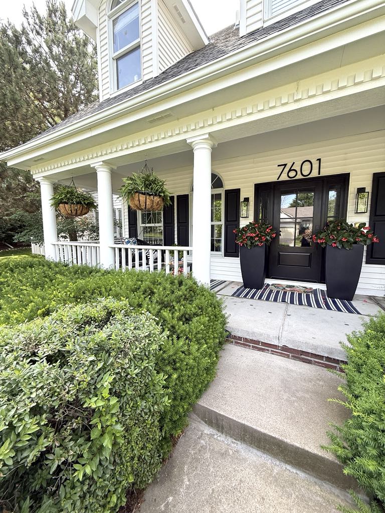 Front porch door with two flower filled planters on either side.