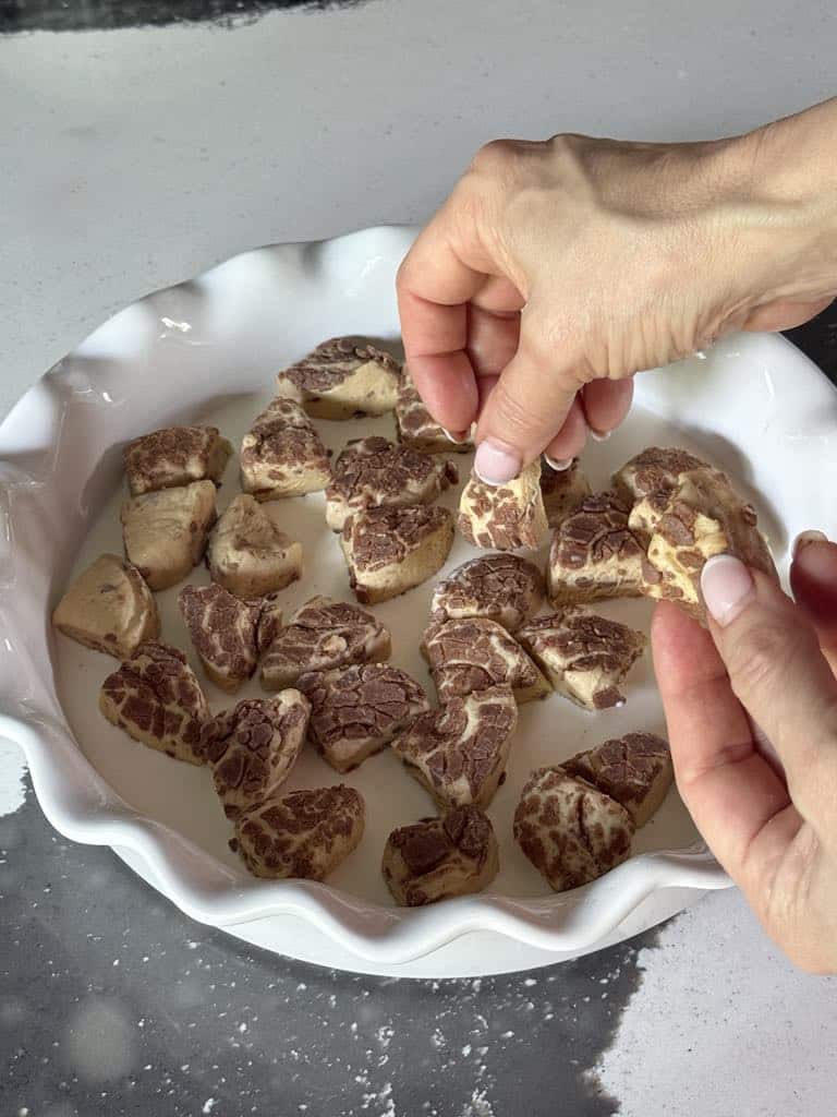 Placing pieces of cinnamon roll dough into bottom of baking dish.