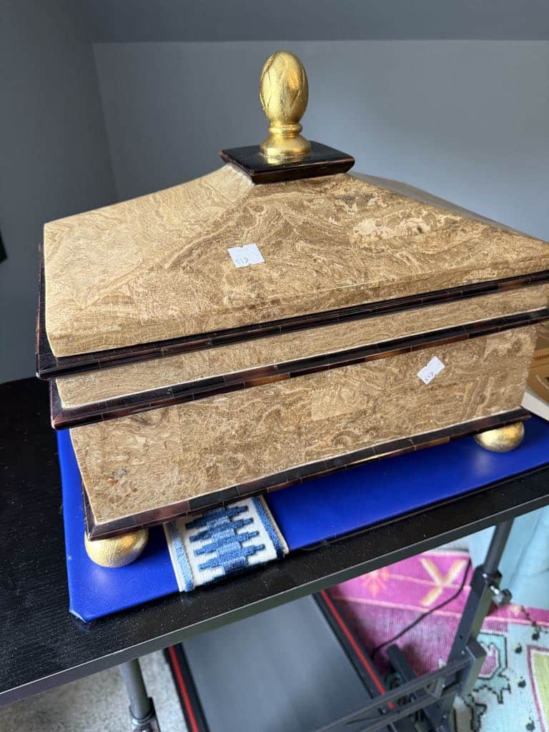 A thrift store decor box with a gold knob on top and gold bun feet.