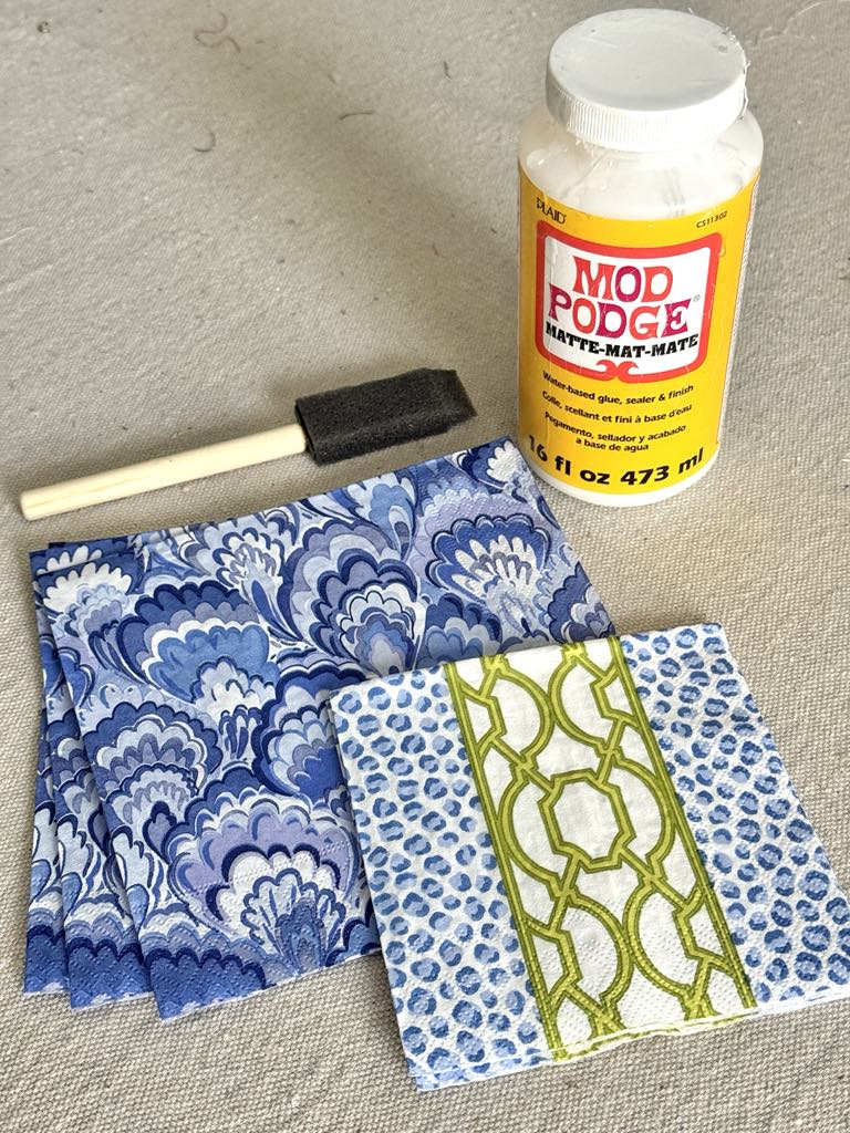 A bottle of Mod Podge with paper napkins and a foam brush.
