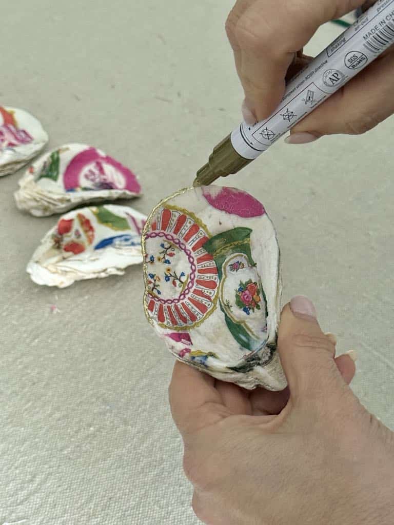Using a gold paint pen to outline the edge of decoupage shells.