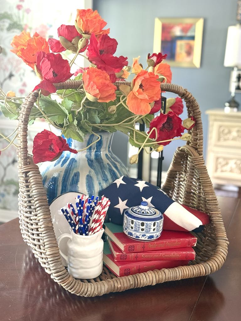 A patriotic centerpiece with a flag, poppies, and woven basket on a dining room table.