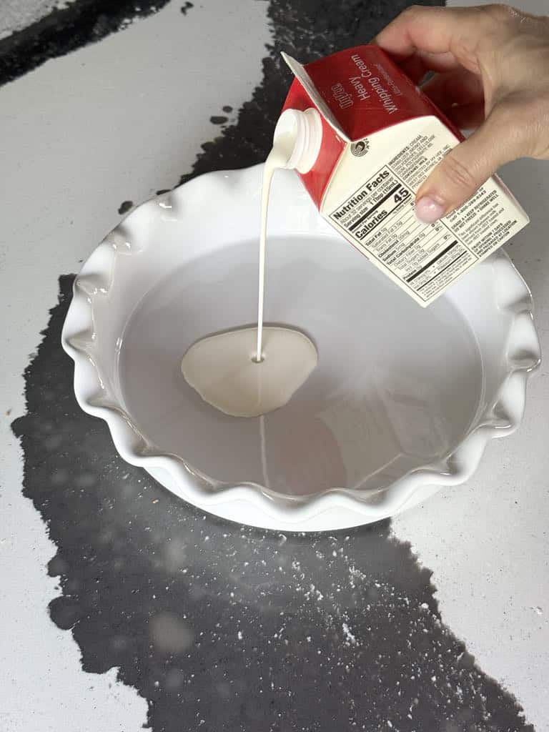 Pouring cream into the bottom of a baking dish.