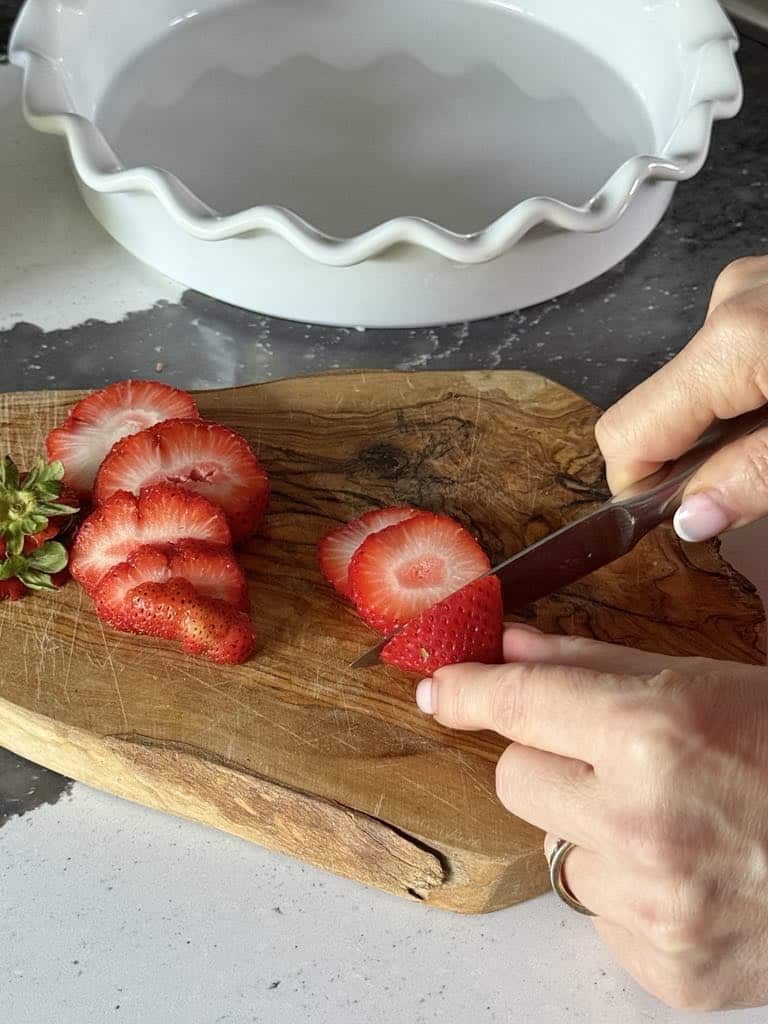 Slicing fresh strawberries for cinnamon roll casserole.
