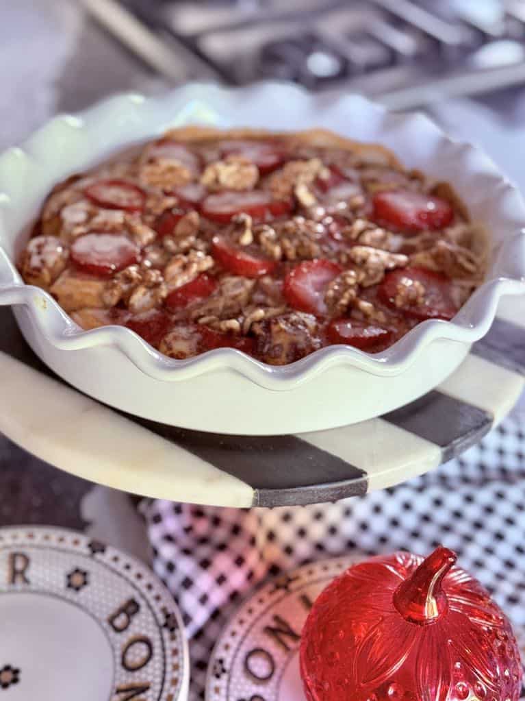 Strawberry Cinnamon Roll Casserole displayed on a pedestal.