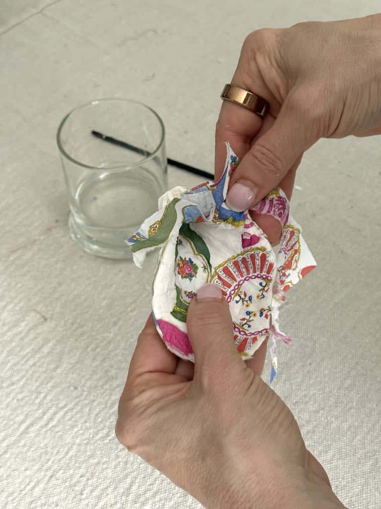 Pressing a piece of paper napkin to the inside of a decoupaged shell.