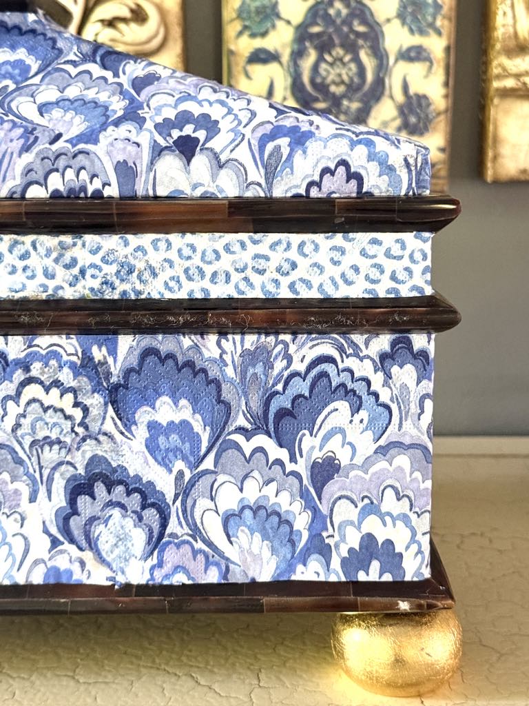 A lidded decor box from a thrift store with two patterns decoupaged on the side.