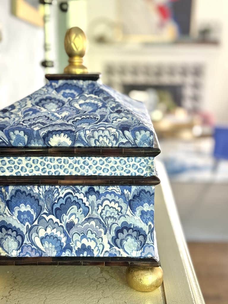 A thrift store decor lidded box that has been decoupaged with blue and white paper napkins.