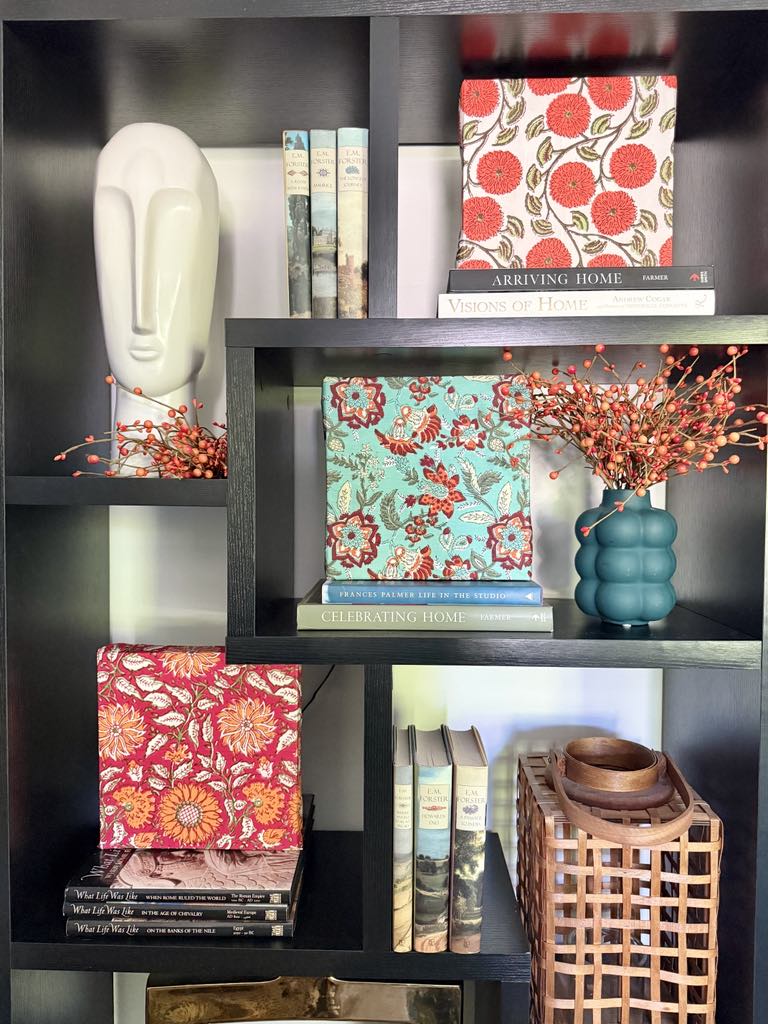 Block print fabric napkins wrapped around square canvases and styled in a bookcase.