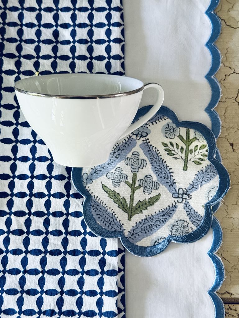 A blue and white block print coaster layered on top of blue and white linens.