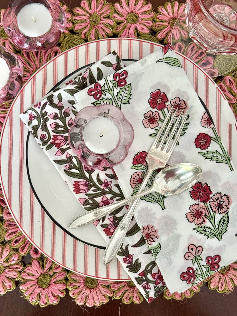 A table setting with layered block print fabric napkins decorating the top of a stack of plates.